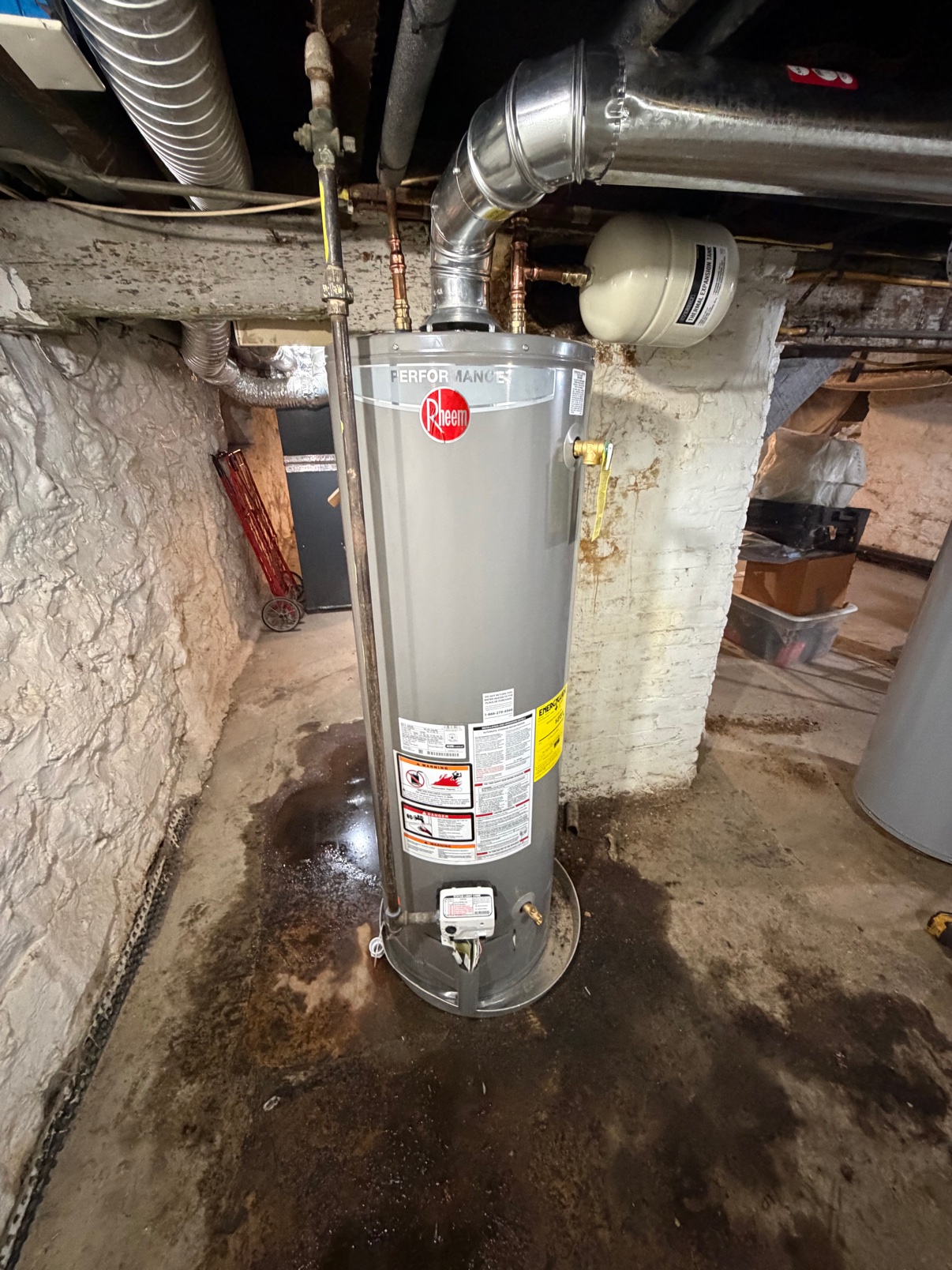 After — a new Rheem water heater installed in the same spot, with an expansion tank